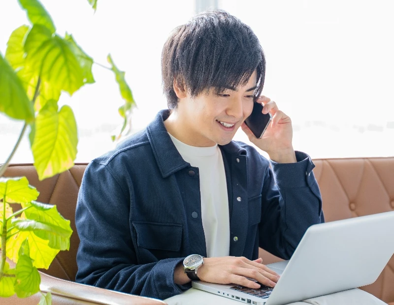 男性が在宅でパソコンを見ながら他の人とやり取りをしている様子