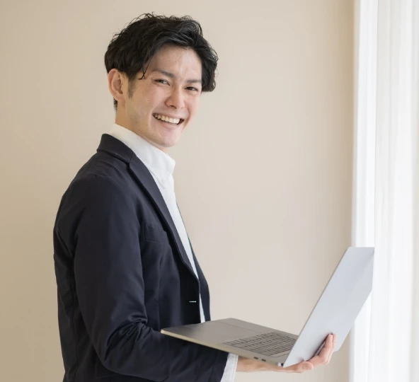 ビジネスマンが窓の前でノートパソコンを持っている様子